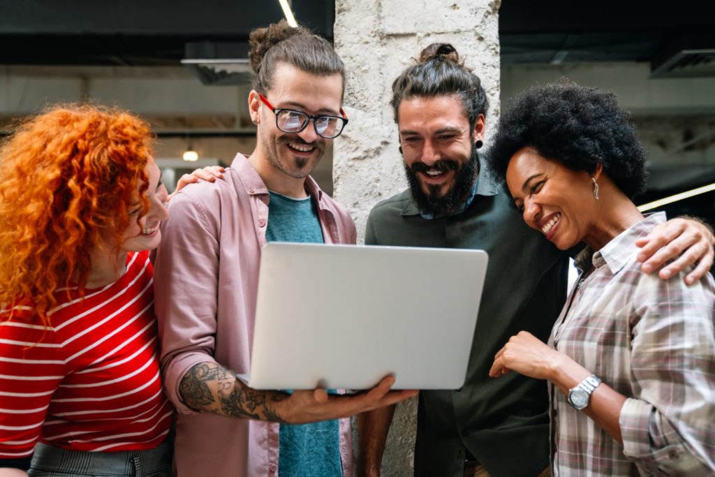 Smiling group of diverse businesspeople going over paperwork together, working in corporate office